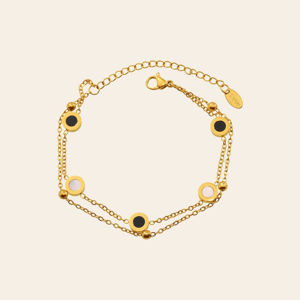 The Eclipse Bracelet, a double gold chain with black and shell discs