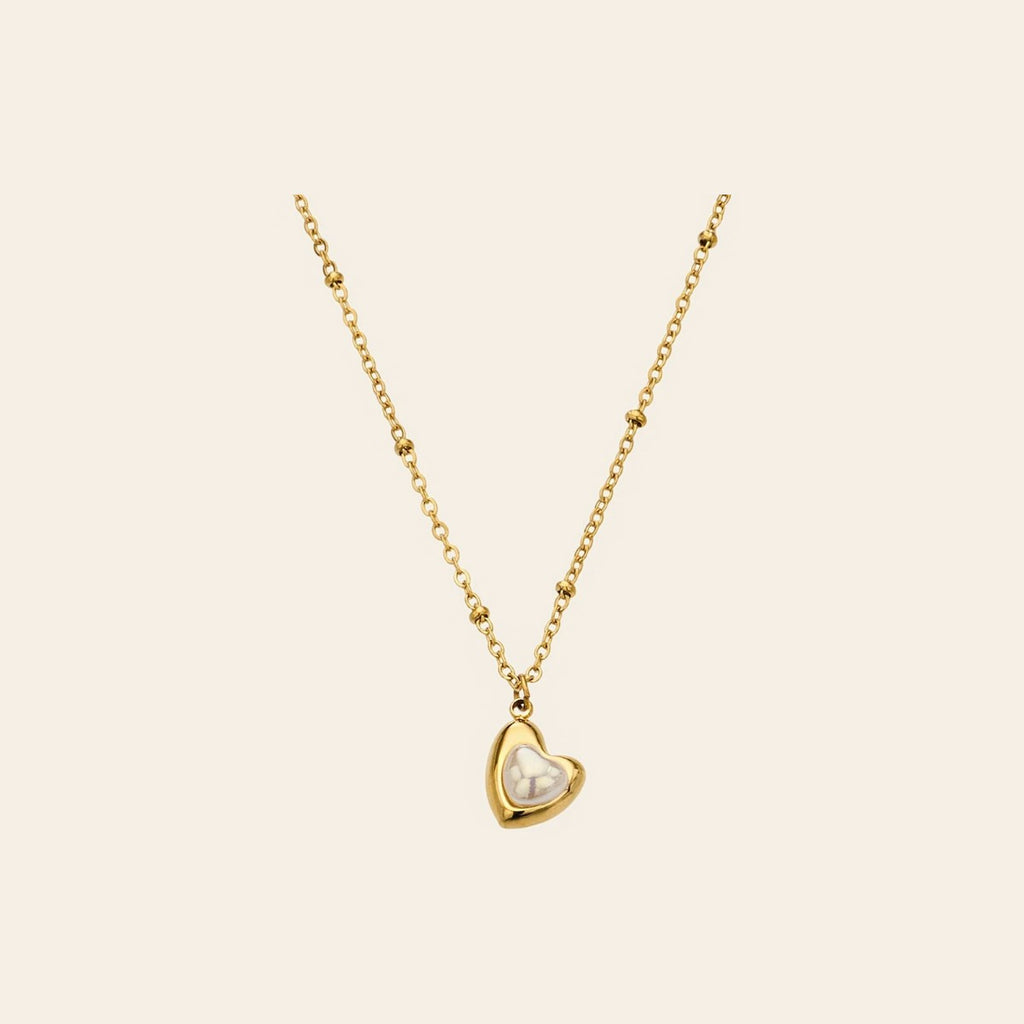 The Sweetheart Necklace, a pearly heart pendant on a gold satellite chain